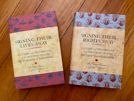 The two autographed hardcovers fanned out lying side by side, showing the front covers of Signing Their Lives Away (Declaration of Independence signers) and Signing Their Rights Away (U.S. Constitution signers) in near-pristine dust jackets.